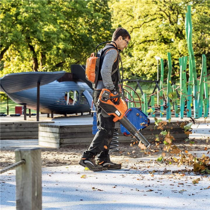 Man with a battery leaf blower on a play ground